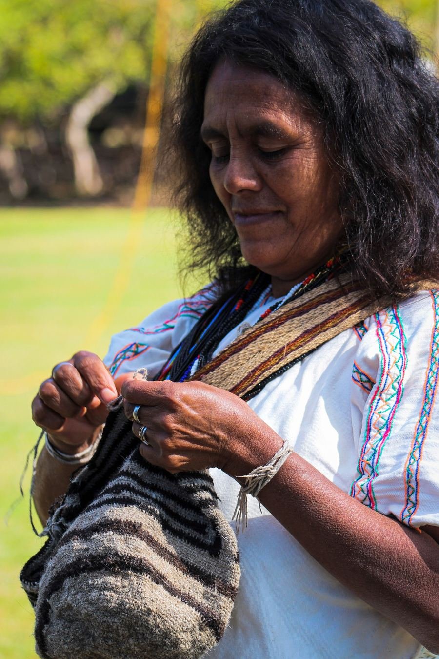 Artesana tejiendo una mochila a mano al aire libre